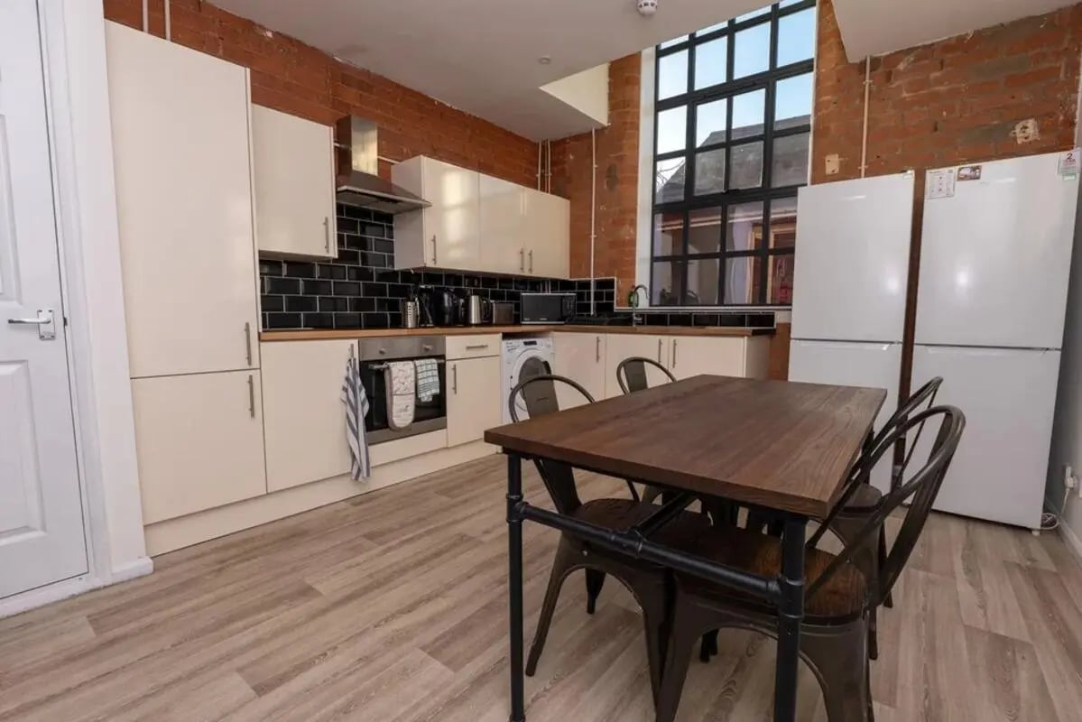 Kitchen with white cabinets oven washing machine and table Kitchen at Bertrand Russell House in Nottingham Student Accommodation