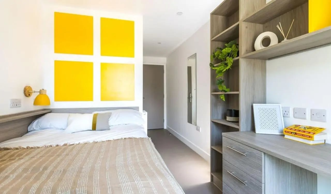 Bed desk shelves and yellow wall art bedroom at Timber Yard in Bristol Student Accommodation