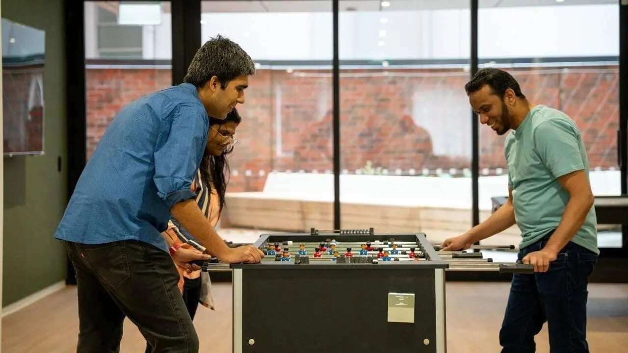 Three people playing foosball game table room at UniLodge Auckland Central in Auckland Student Accommodation