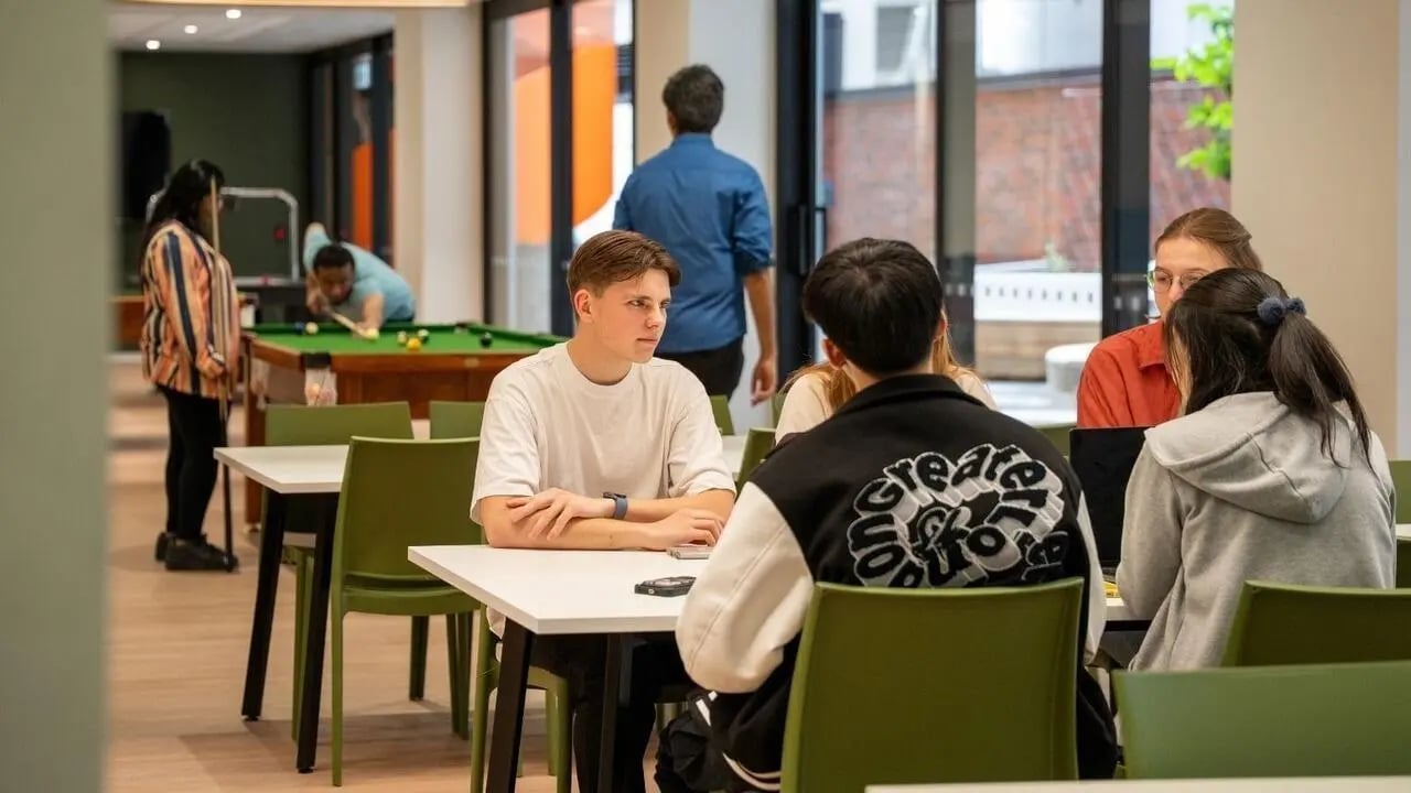 Students playing pool and sitting at tables communal area at UniLodge Auckland Central in Auckland Student Accommodation