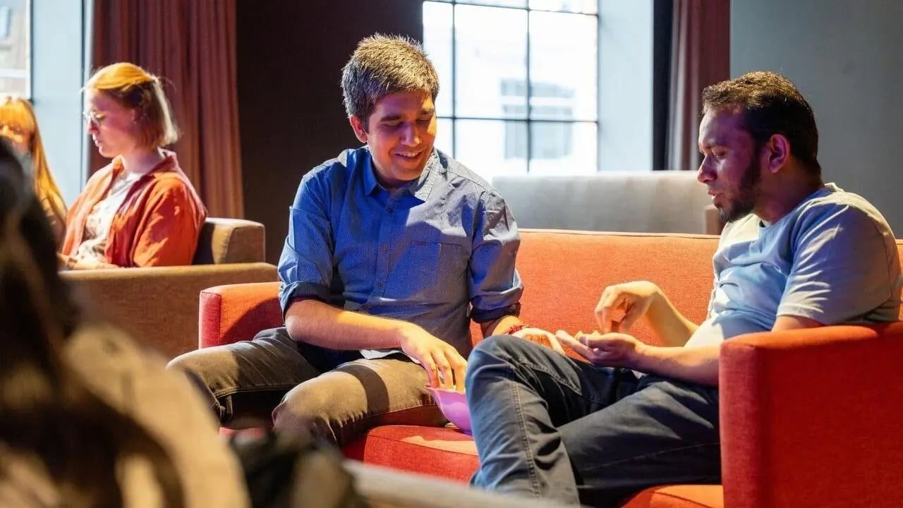 Students talking on orange sofas living room at UniLodge Auckland Central in Auckland Student Accommodation