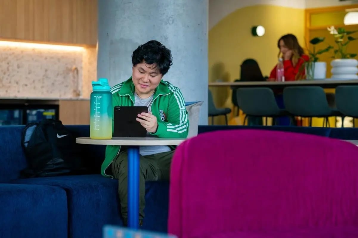 Man with tablet and water bottle communal area at Scape Kensington in Sydney Student Accommodation