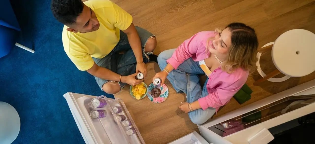 People sharing snacks and drinks in a living area. at Scape Kensington in Sydney Student Accommodation