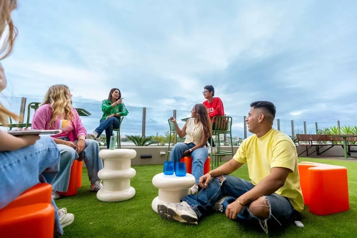 Students relaxing outdoors with coffee tables and seating living room at Scape Kensington in Sydney Student Accommodation