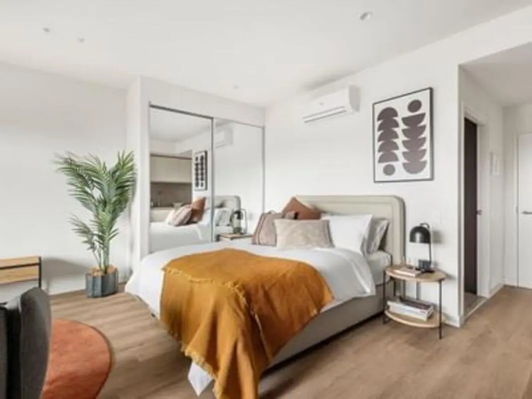 Bed with orange throw plant mirrors bedroom at Caulfield Place in Melbourne Student Accommodation