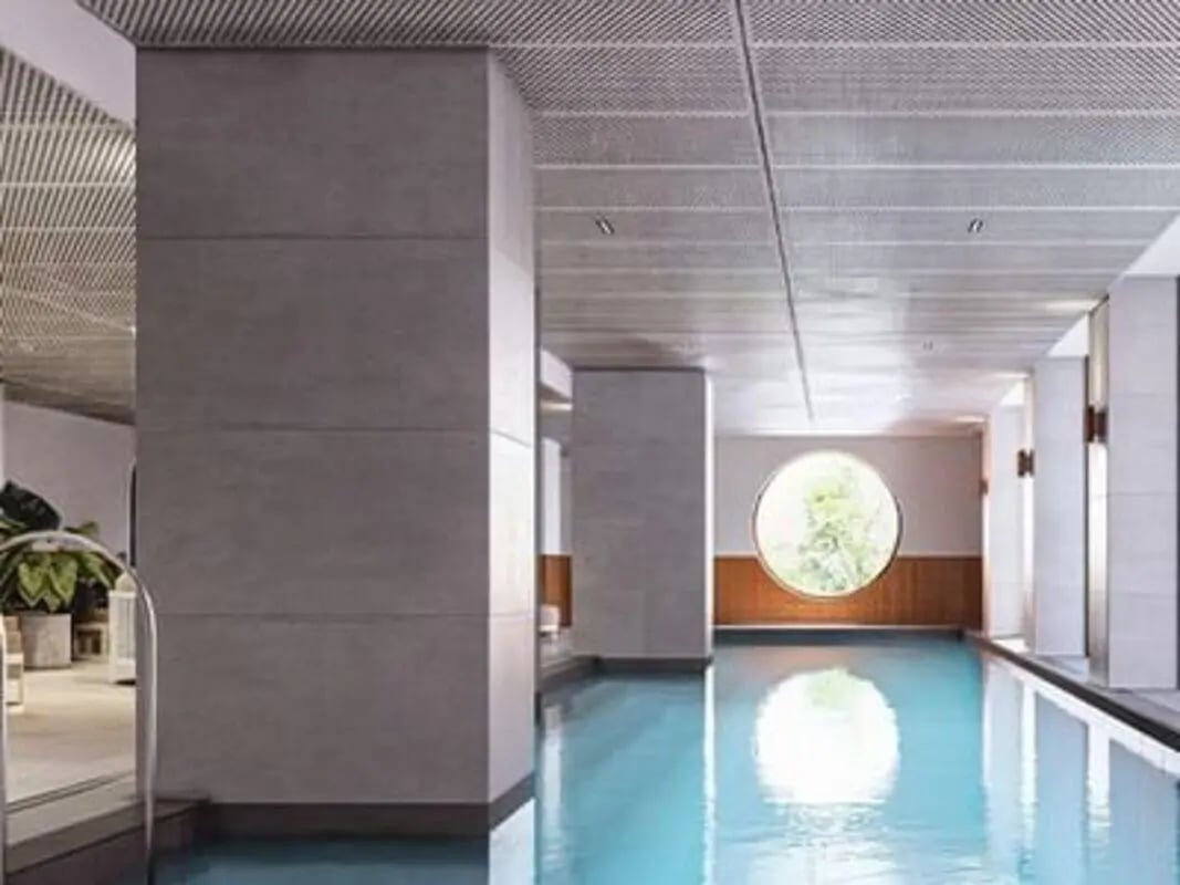 Indoor swimming pool with circular window and plants swimming pool at Caulfield Place in Melbourne Student Accommodation