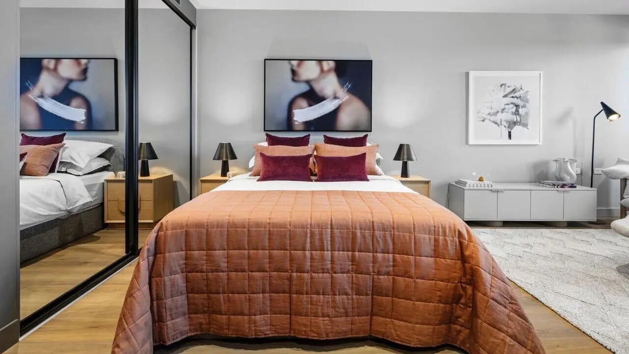 Queen bed with burnt orange quilt and pillows Bedroom at Indi South Bank in Melbourne Student Accommodation