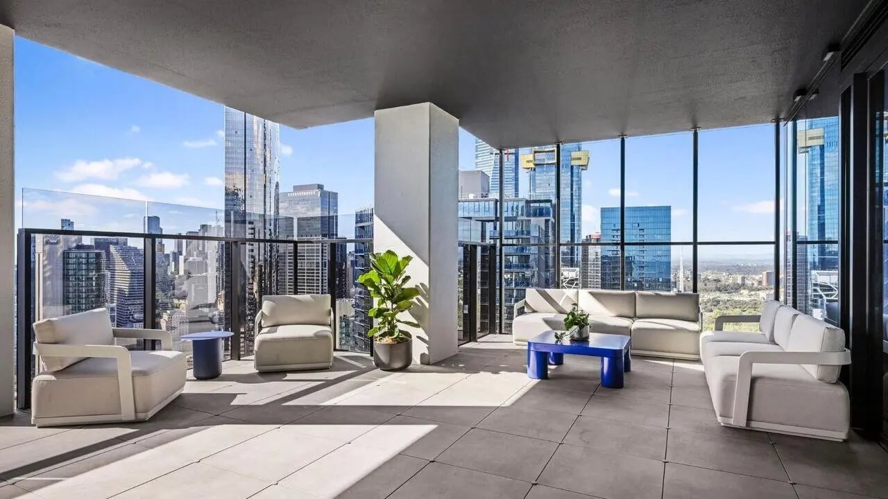 White couches blue table plant balcony living room at Indi South Bank in Melbourne Student Accommodation