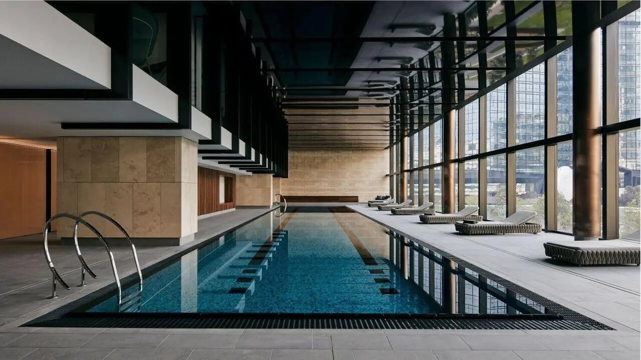 Indoor swimming pool with loungers and city view at West Tower, Melbourne Quarter in Melbourne Student Accommodation
