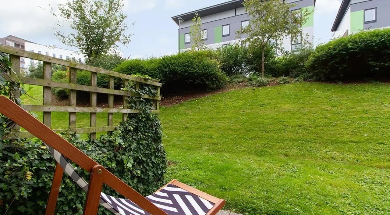 Wooden fence deck chair green lawn exterior at The Green in Bradford Student Accommodation