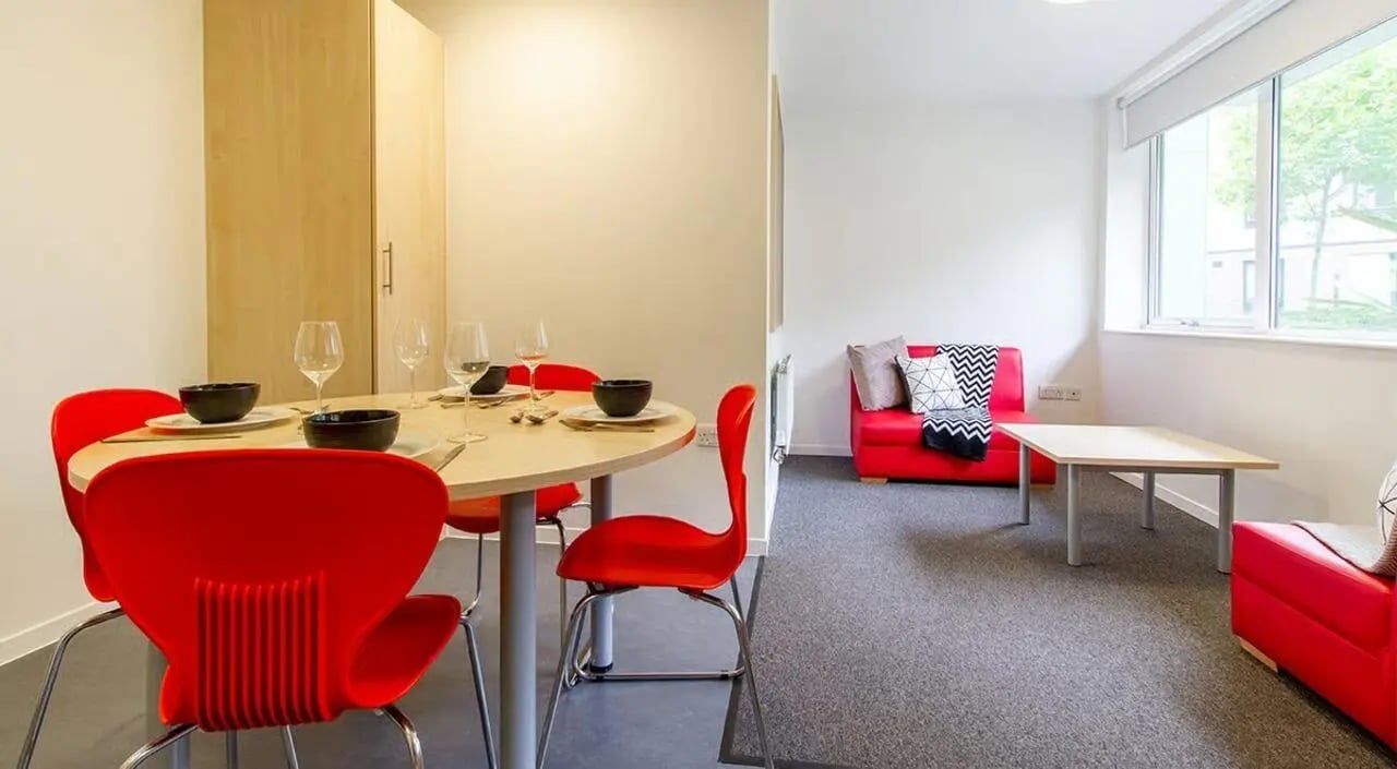 Dining table red chairs red sofas living room at The Green in Bradford Student Accommodation