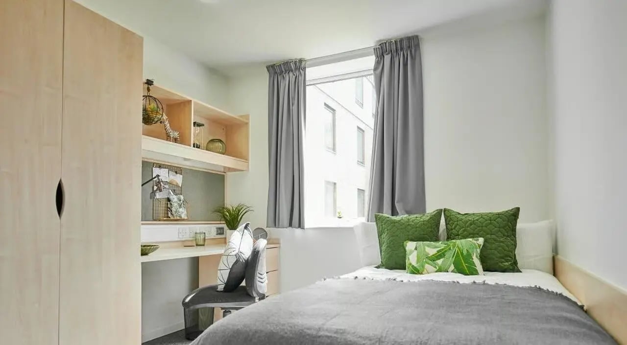 Wardrobe desk bed with green pillows bedroom at The Green in Bradford Student Accommodation