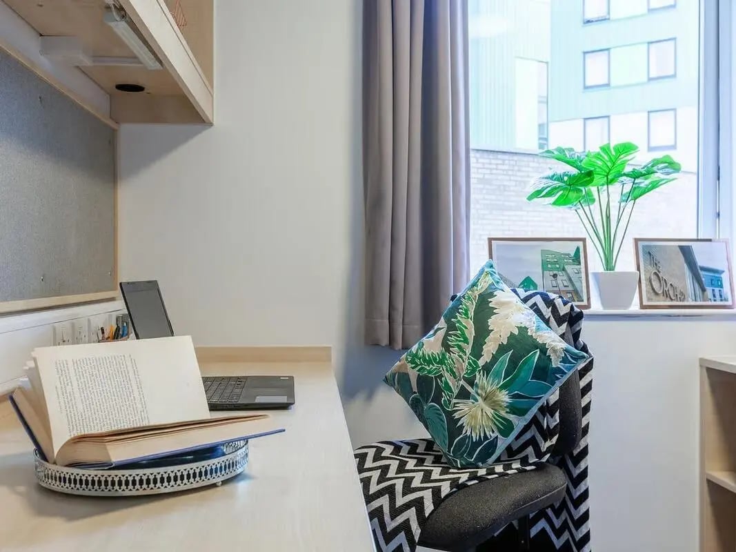 Desk with laptop book and chair study area at The Green in Bradford Student Accommodation