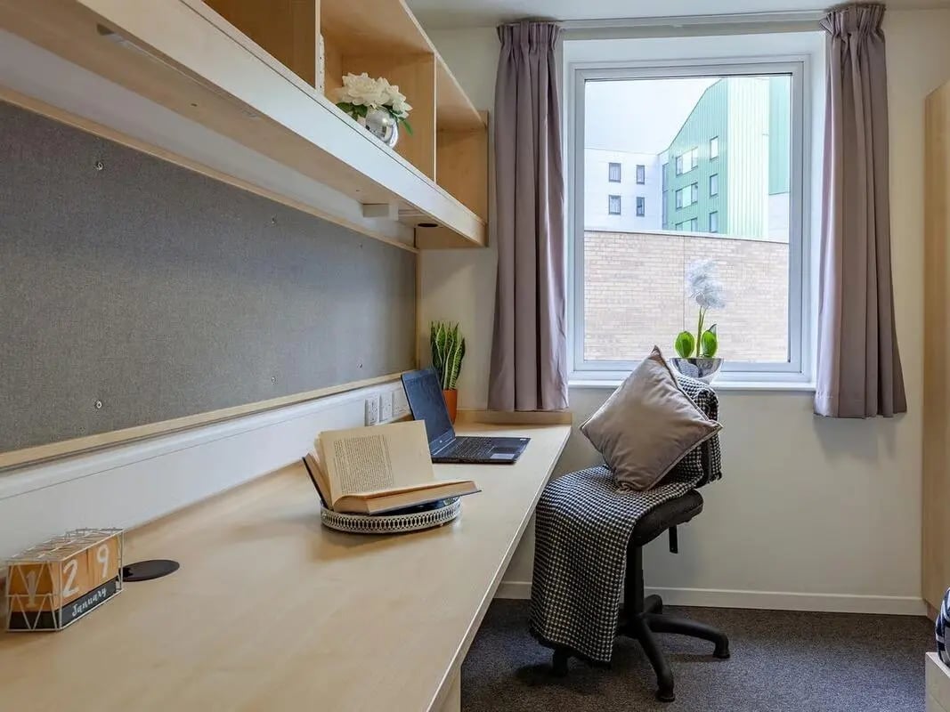 Desk with laptop book calendar and chair study area at The Green in Bradford Student Accommodation