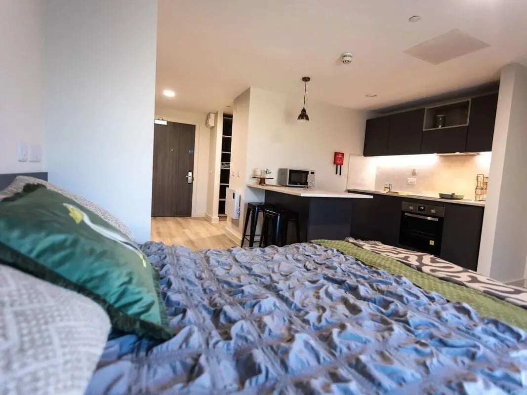 Bed kitchen cabinets microwave oven and stools studio apartment at Stanley Studios - Portsmouth in Portsmouth Student Accommodation