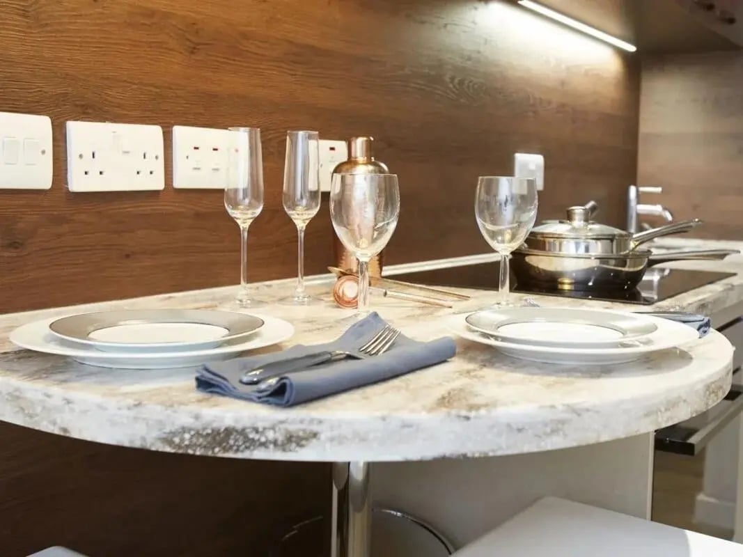 Table with plates glasses and shaker kitchen at Woodside House in Glasgow Student Accommodation