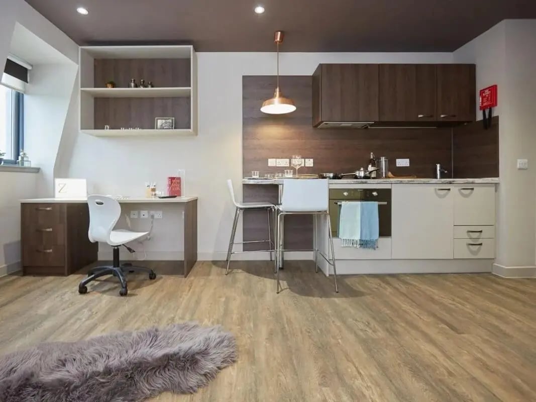 Desk chair shelves kitchen counter and stools Studio apartment at Woodside House in Glasgow Student Accommodation