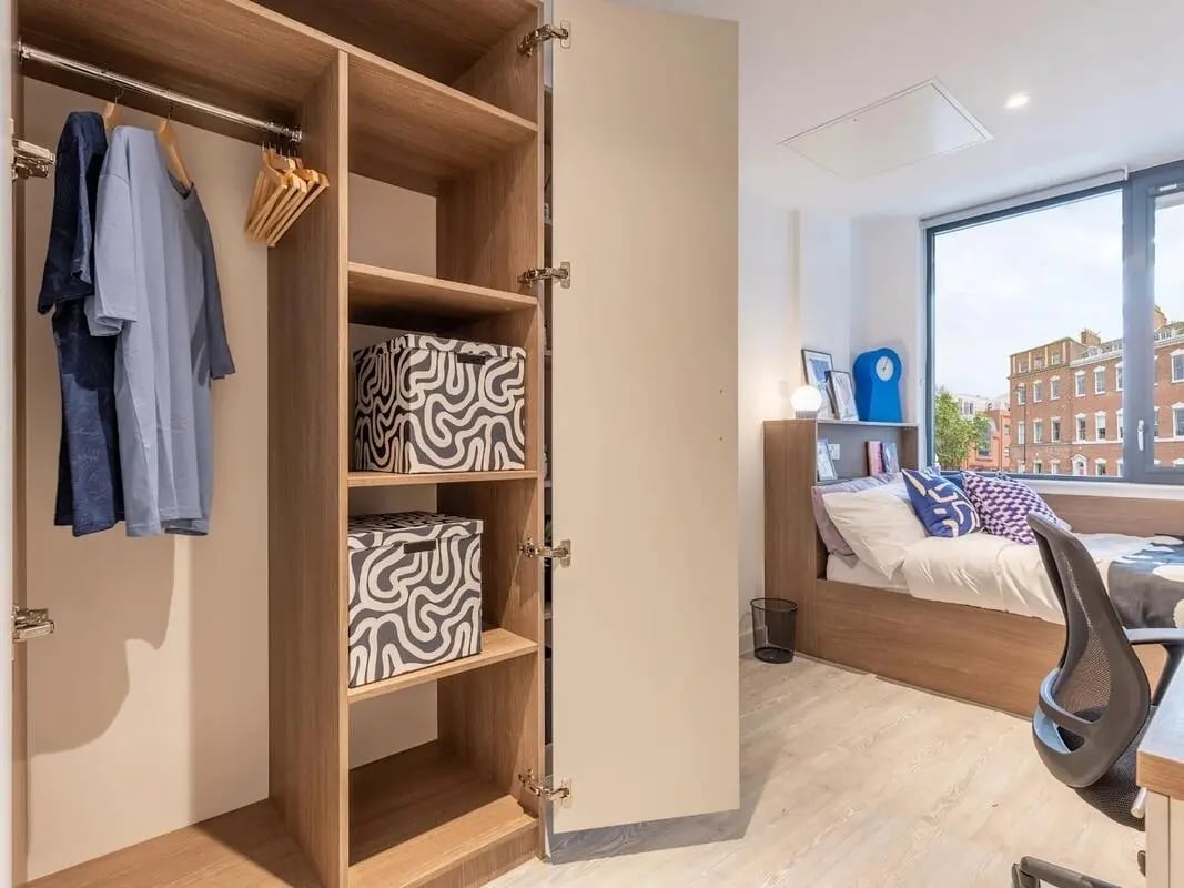 Wardrobe with clothes and boxes beside bed bedroom at Glassworks in Bristol Student Accommodation