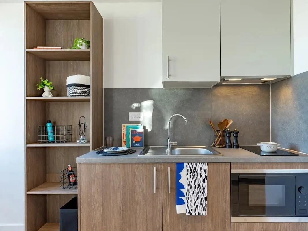 Bookshelf sink microwave and cabinets kitchen at Glassworks in Bristol Student Accommodation