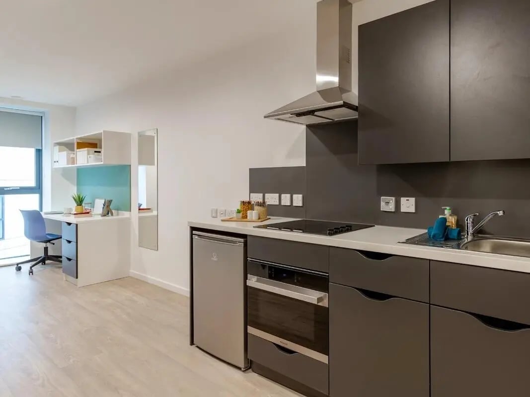 Desk chair mirror cabinets fridge oven and sink kitchen at Pavilion Court London in London Student Accommodation