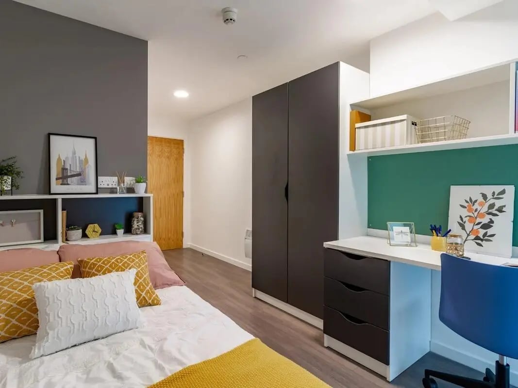 Bed with yellow pillows and desk Bedroom at Pavilion Court London in London Student Accommodation