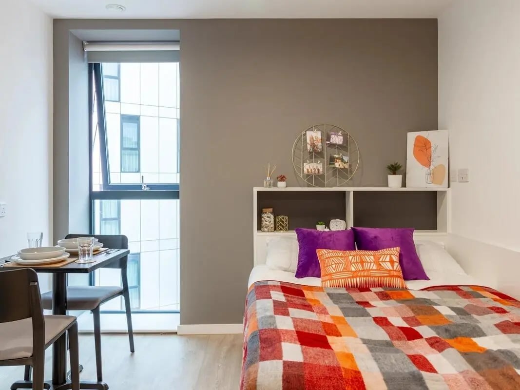 Bed with colorful throw purple pillows and table Bedroom at Pavilion Court London in London Student Accommodation