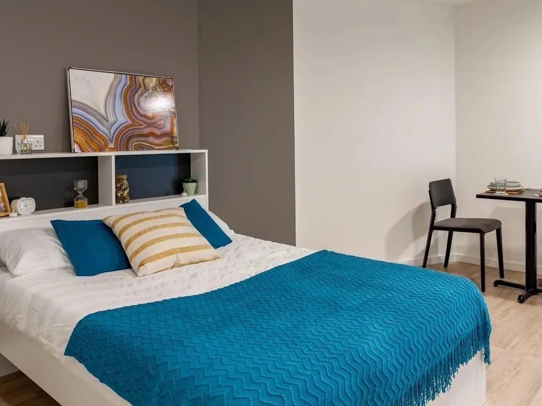 Bed pillows artwork shelves table chair bedroom at Pavilion Court London in London Student Accommodation