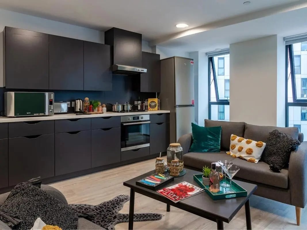 Modern kitchen with dark cabinets and sofa living area at Pavilion Court London in London Student Accommodation