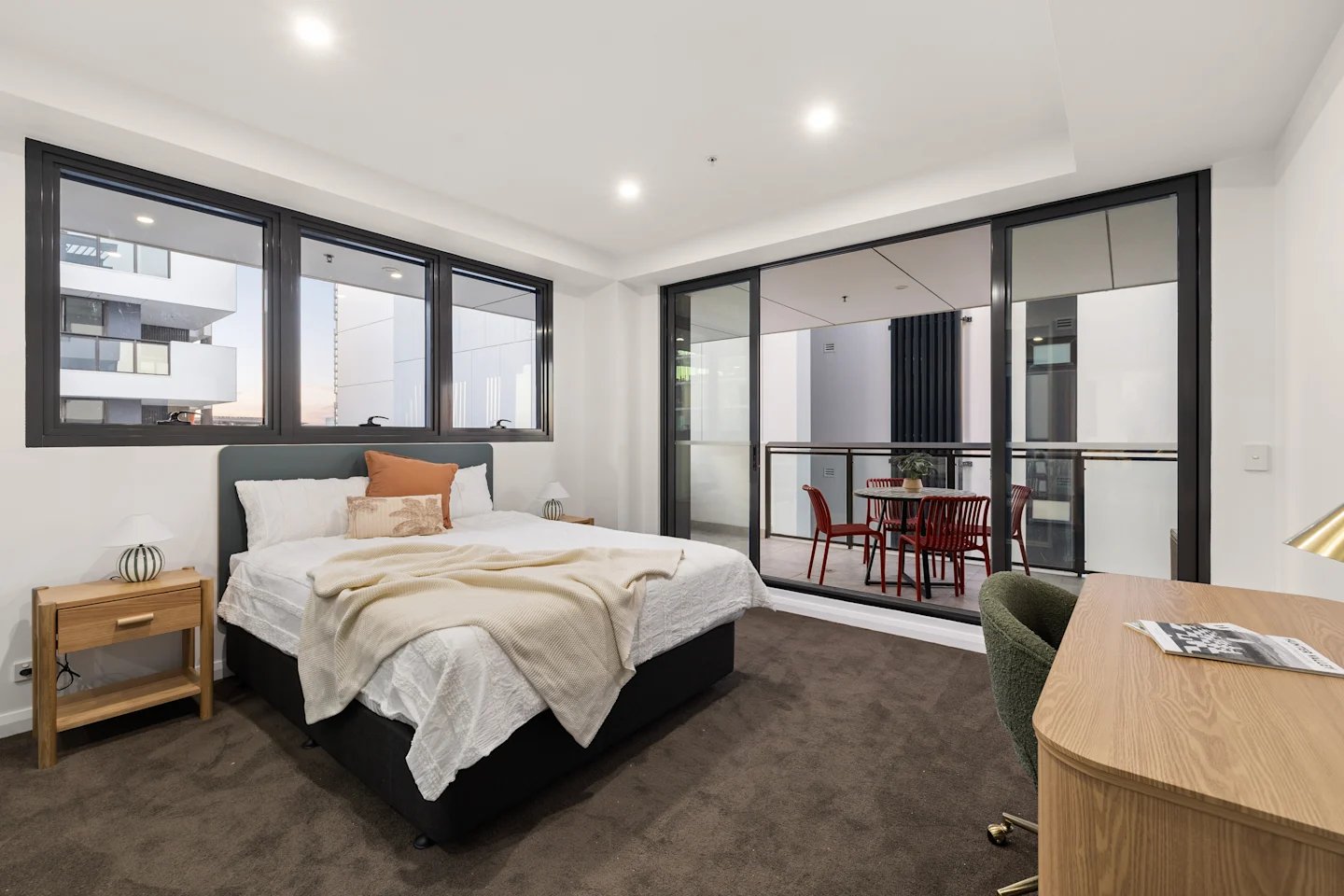 Bed desk chair balcony with red chairs bedroom at UKO Parramatta Central in Sydney Student Accommodation