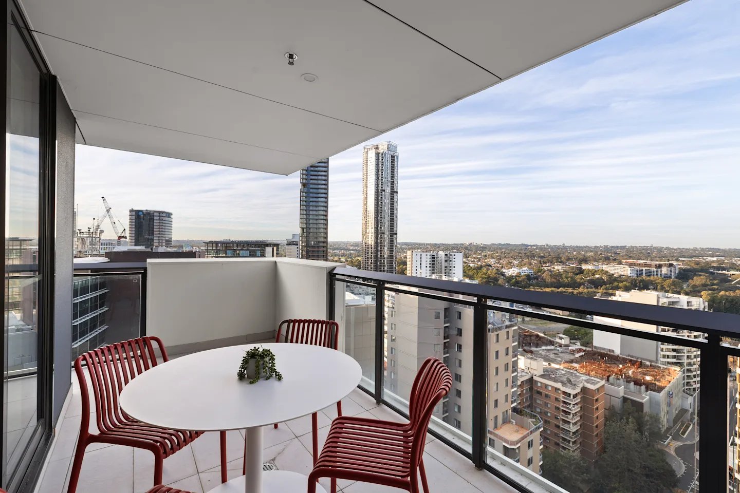 Balcony with white table red chairs exterior at UKO Parramatta Central in Sydney Student Accommodation