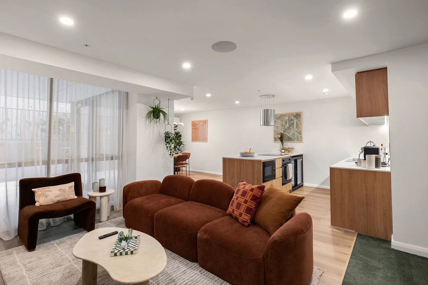 Sofa coffee table kitchen island artwork living area at UKO Parramatta Central in Sydney Student Accommodation