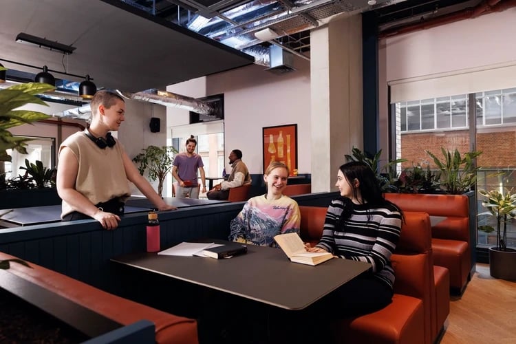 Students sitting at tables in communal area living room at Hayloft Point in London Student Accommodation