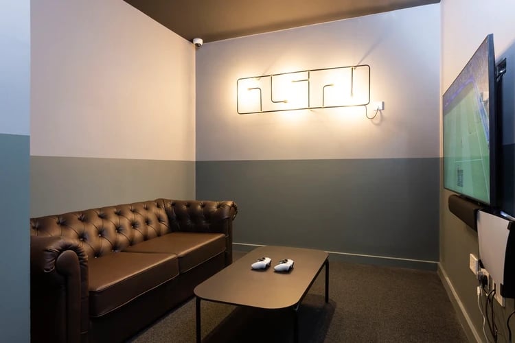 Brown sofa coffee table controllers TV living room at Hayloft Point in London Student Accommodation