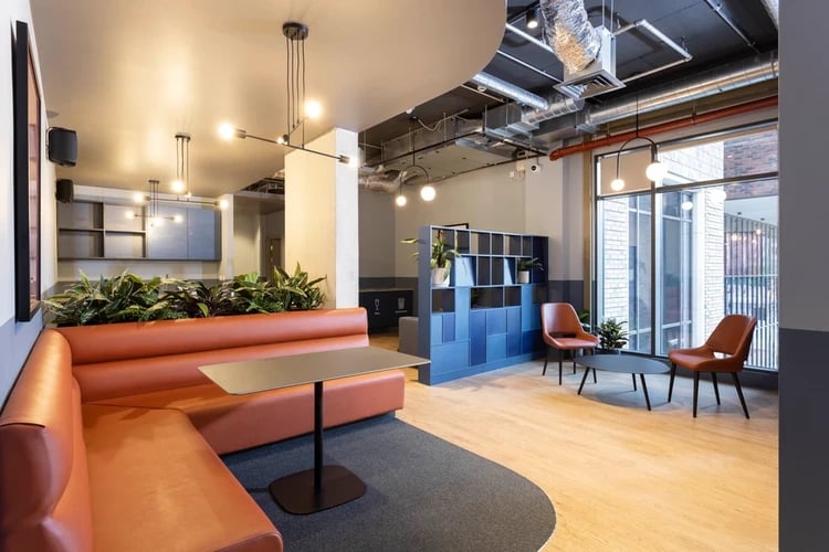 Orange seating area tables chairs shelving common area at Hayloft Point in London Student Accommodation