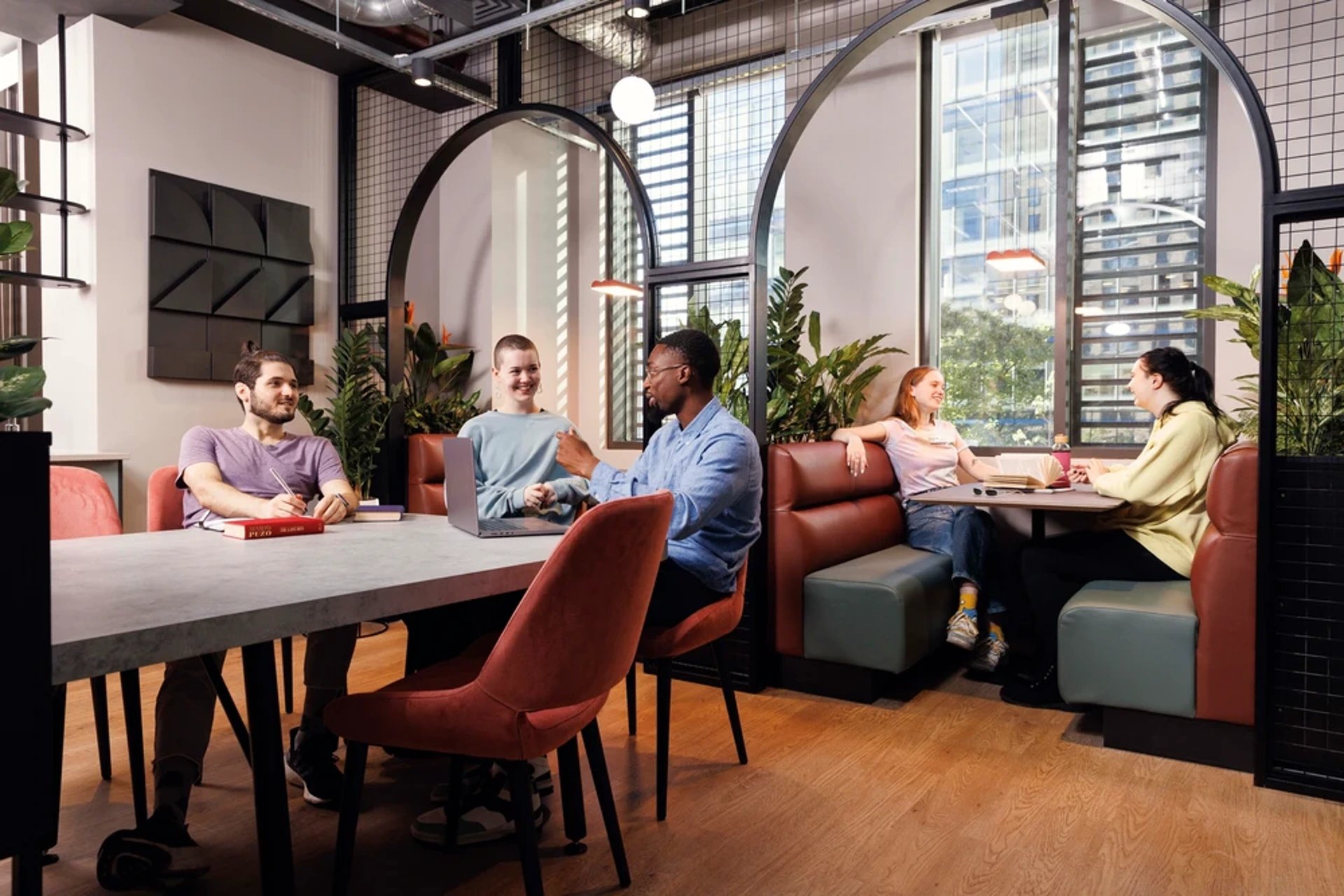Students studying around a table and booths living room at Hayloft Point in London Student Accommodation