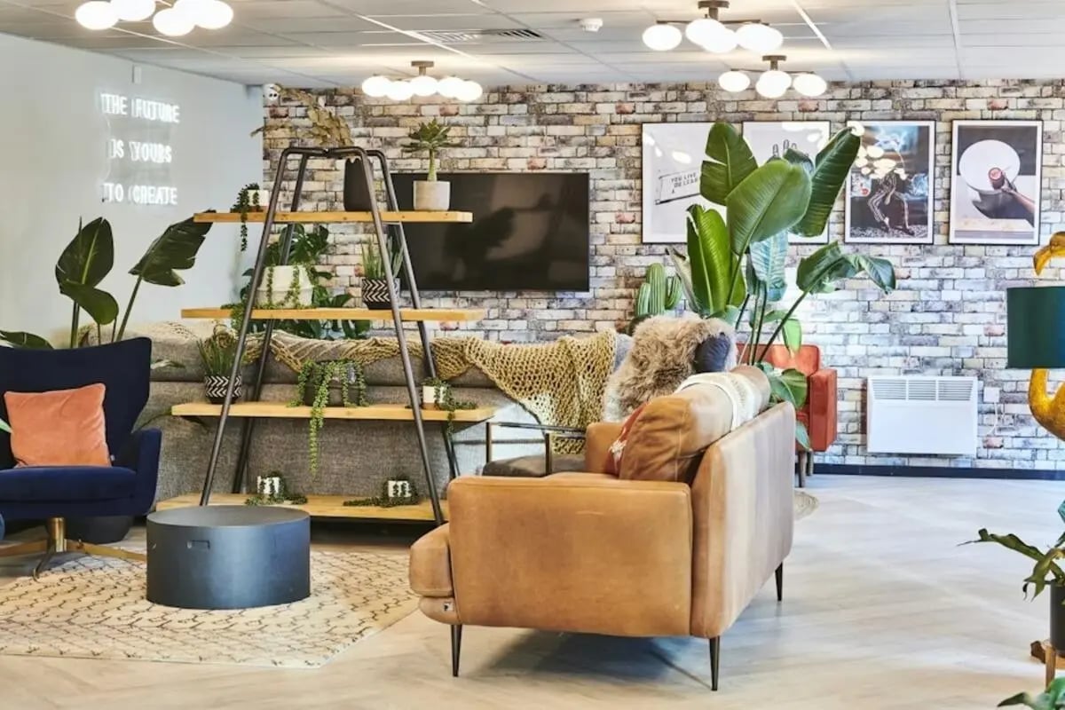Brown sofa plant shelf neon sign living room at Capital Gate in Liverpool Student Accommodation