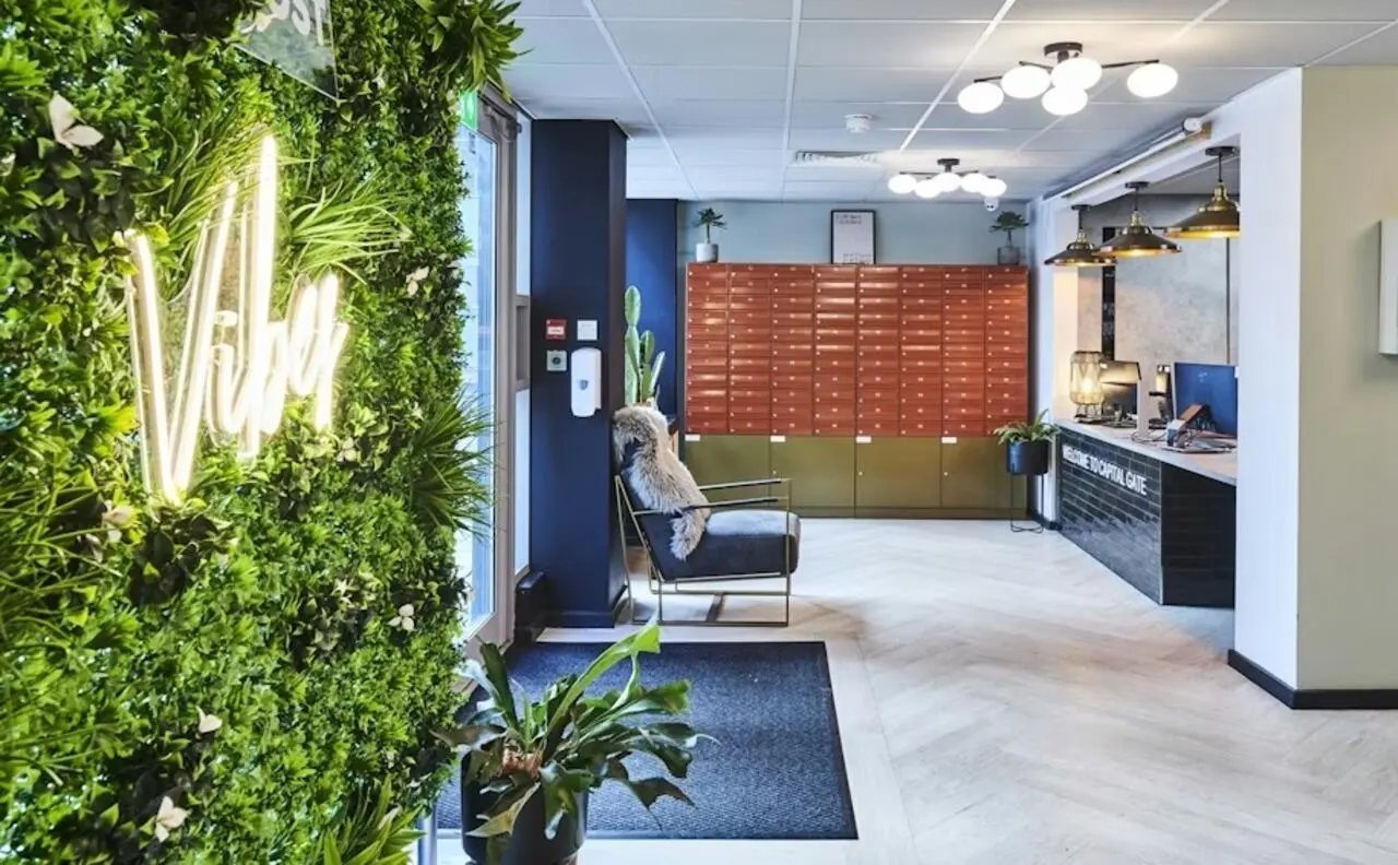 Green wall with neon sign lobby area exterior at Capital Gate in Liverpool Student Accommodation