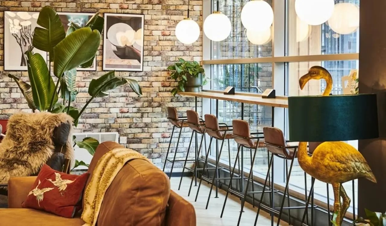 Sofa plants bar stools flamingo lamp lounge area at Capital Gate in Liverpool Student Accommodation