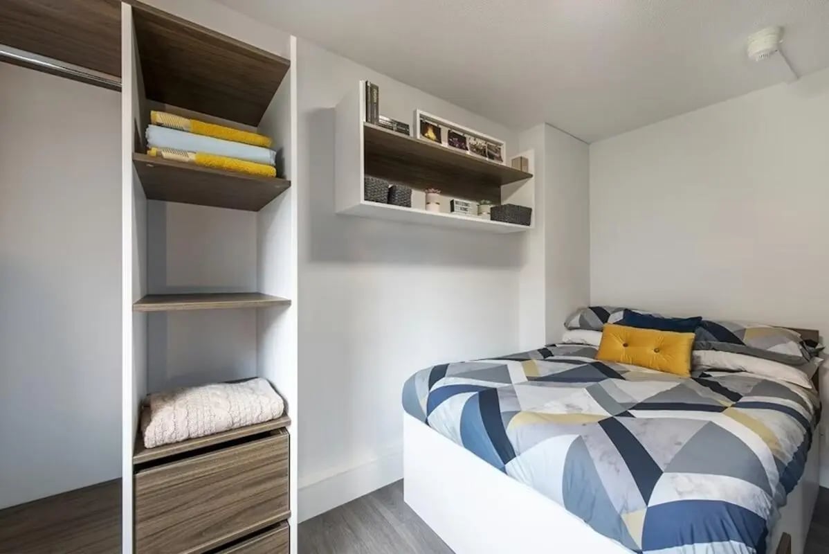 Bed with patterned duvet and yellow pillow Bedroom at Regents Court in Leicester Student Accommodation