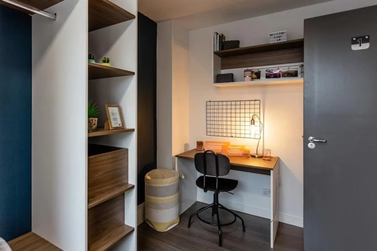 Desk with chair shelves and laundry basket bedroom at Regents Court in Leicester Student Accommodation