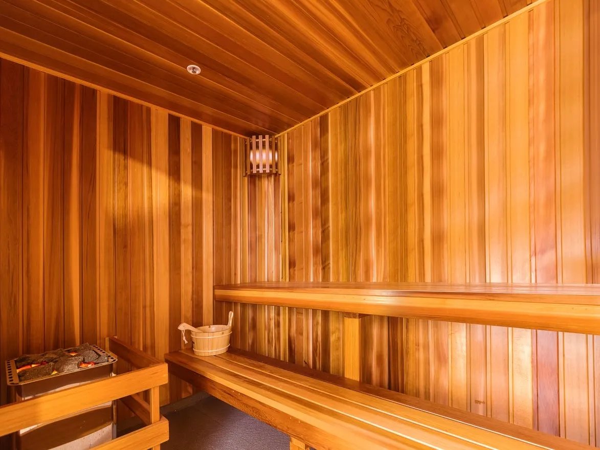 Wooden sauna benches heater bucket and light fixture Sauna at Belong Waterloo in Sydney Student Accommodation