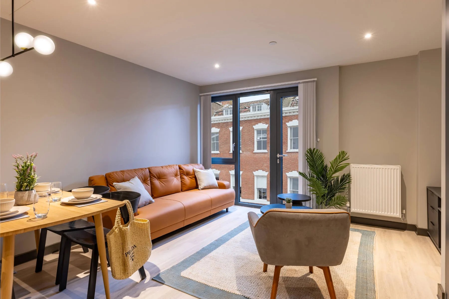 Sofa dining table chairs rug and plant Living Room at The Port On The Square in Bristol Student Accommodation
