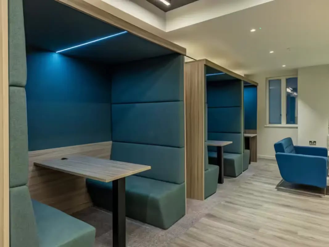 Study booths with blue seating and tables living room at Grosvenor House in London Student Accommodation