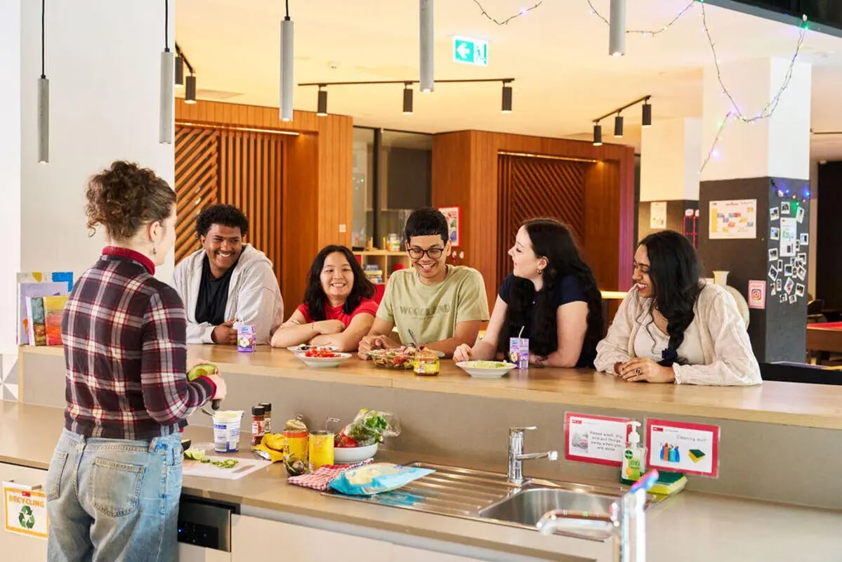 Students chatting at a kitchen counter communal area at UniLodge Royal Melbourne in Melbourne Student Accommodation