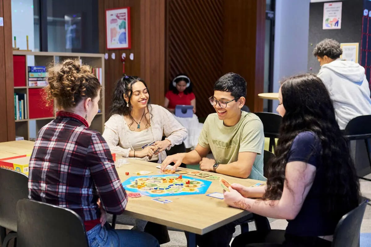 Students playing board game at table common room at UniLodge Royal Melbourne in Melbourne Student Accommodation
