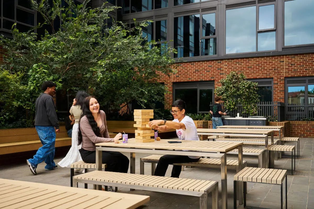 Students play Jenga at tables outdoor courtyard area at UniLodge Royal Melbourne in Melbourne Student Accommodation