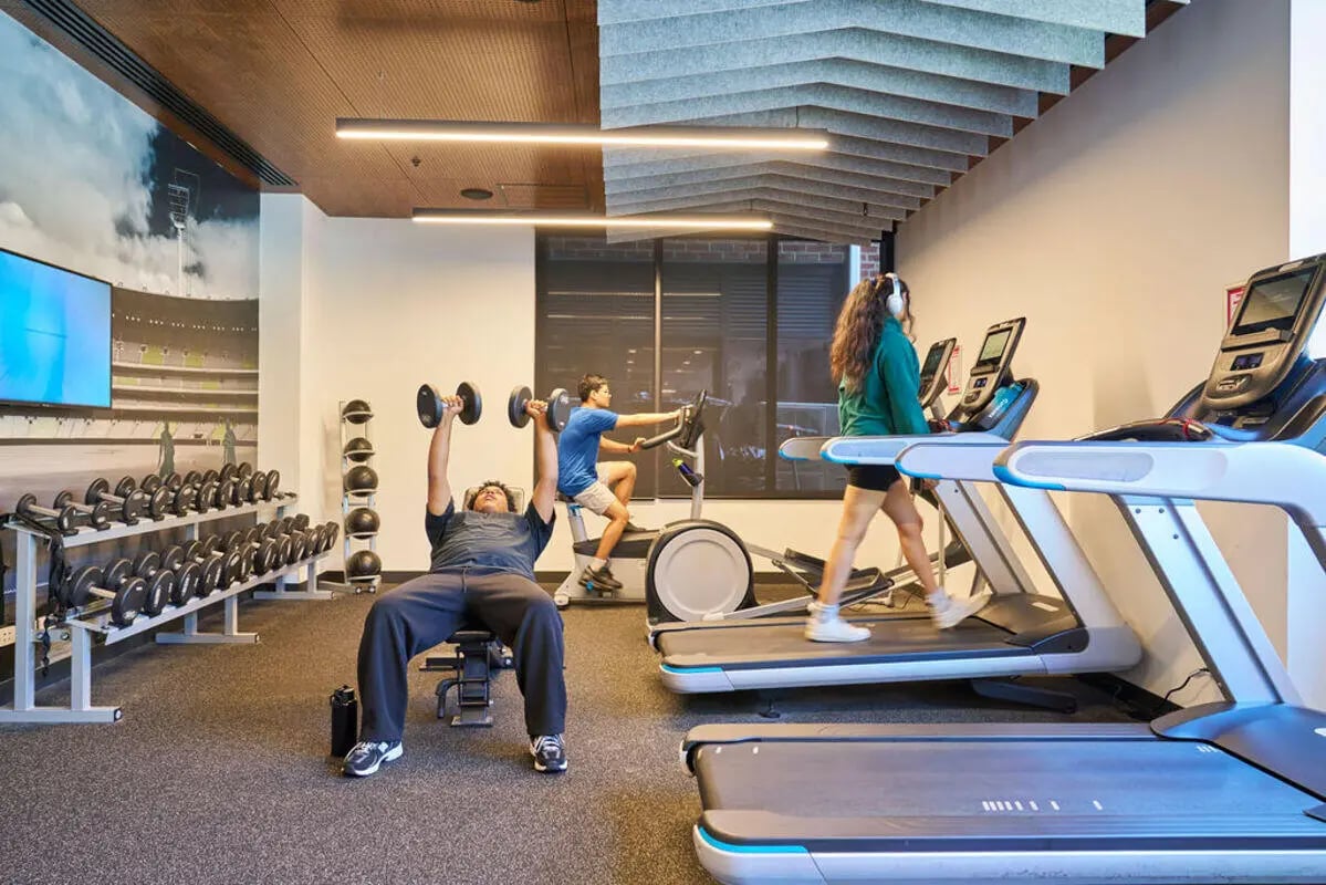 Gym with people lifting weights and running at UniLodge Royal Melbourne in Melbourne Student Accommodation
