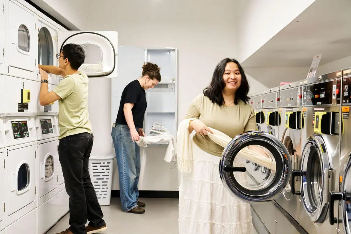 Students in laundry room using machines and ironing board laundry room at UniLodge Royal Melbourne in Melbourne Student Accommodation