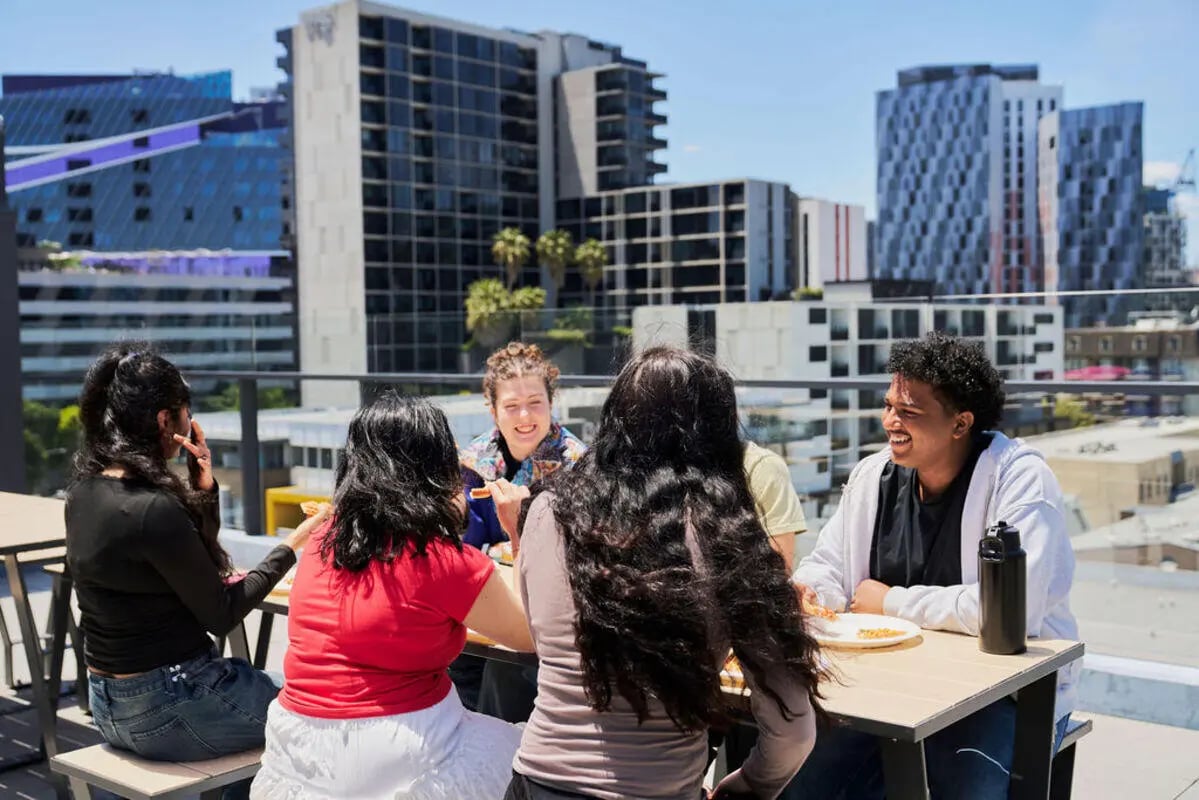 Students eating on rooftop balcony with city view exterior at UniLodge Royal Melbourne in Melbourne Student Accommodation
