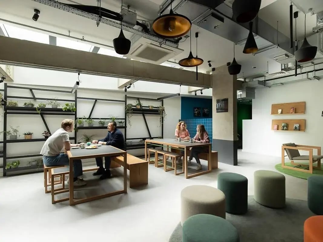 People seated at tables with plants communal area at Element Bermondsey in London Student Accommodation